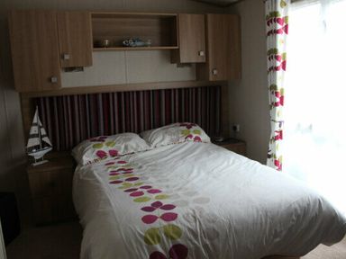 a bedroom with a bed, bedside tables, and window curtains at White Acres Holiday Park - Holiday Accommodation 895, Newquay