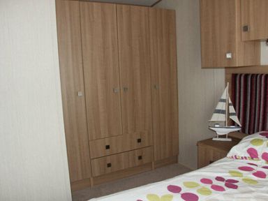 a wooden wardrobe with drawers and a decorative sailboat at White Acres Holiday Park - Holiday Accommodation 895 in Newquay