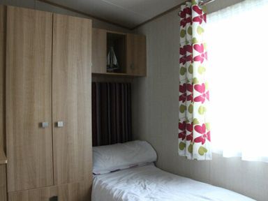 a bedroom with a single bed and a wardrobe at White Acres Holiday Park - Holiday Accommodation 895, Newquay