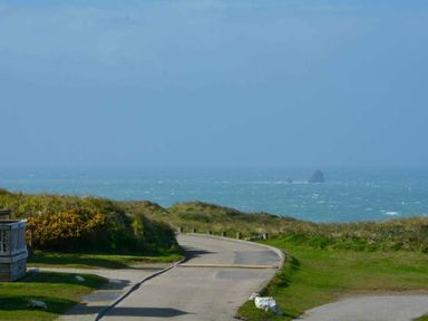 a coastal view with a road leading to the sea and distant rocks at Perran Sands - Holiday Accommodation 8982, Perranporth