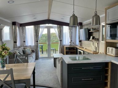 a living room with a dining table and kitchen area at Perran Sands - Holiday Accommodation 8982, Perranporth