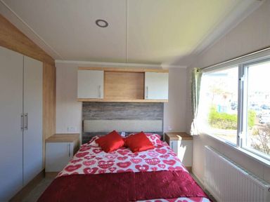 a bedroom with a double bed and decorative pillows at Perran Sands - Holiday Accommodation 8982, Perranporth