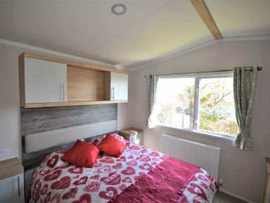 a bedroom with a double bed, heart-patterned bedding, and a window at Perran Sands - Holiday Accommodation 8982, Perranporth