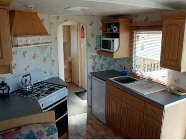 a kitchen with cabinets, a stove, microwave, and sink at Perran Sands - Holiday Accommodation 9159, Perranporth
