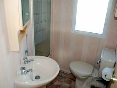 a small bathroom with a sink, toilet, shower, and window at Perran Sands - Holiday Accommodation 9159 in Perranporth
