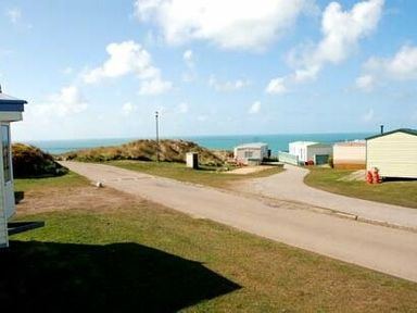 a view of camping trailers and a road with ocean in the background at Perran Sands - Holiday Accommodation 9159 in Perranporth