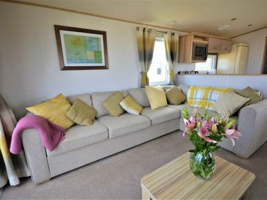 a living room with a sofa and flowers on a table at Perran Sands - Holiday Accommodation 9657 in Perranporth
