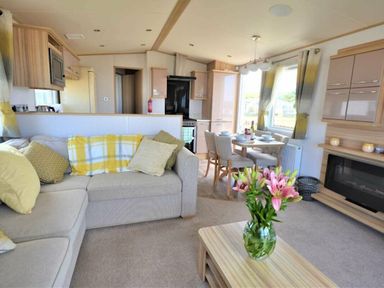a living room with a sofa, coffee table, and dining area at Perran Sands - Holiday Accommodation 9657 in Perranporth
