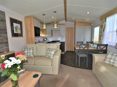 a living room with a sofa, dining area, and kitchen at Perran Sands - Holiday Accommodation 9871 in Perranporth