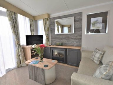 a living room with a television, a mirror, and a sofa at Perran Sands - Holiday Accommodation 9871 in Perranporth