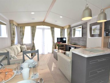 a living room with a sofa, TV, and dining table at Perran Sands - Holiday Accommodation 9871 in Perranporth