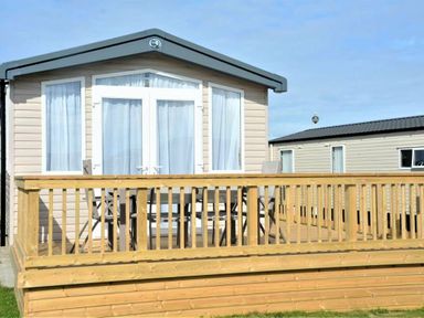 a holiday cabin with a wooden deck and seating outside at Perran Sands - Holiday Accommodation 9871 in Perranporth