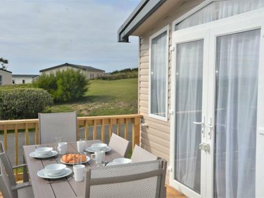 a dining area with a table set for breakfast on a deck at Perran Sands - Holiday Accommodation 9871 Perranporth