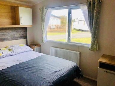 a bedroom with a bed, window, radiator, and storage at Perran Sands - Holiday Accommodation 9871, Perranporth