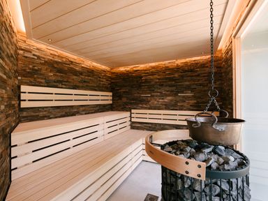 A sauna with wooden benches and a stone wall at Garden Pod in Waltham