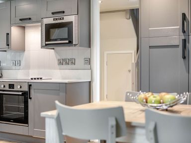 A kitchen with appliances and a table with a bowl of apples at St Ives Studio in Praze-An-Beeble