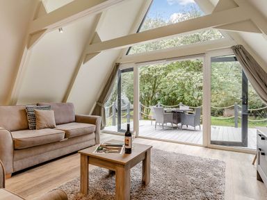 A living room with a sofa and table overlooking outdoor furniture at St Ives Studio in Praze-An-Beeble