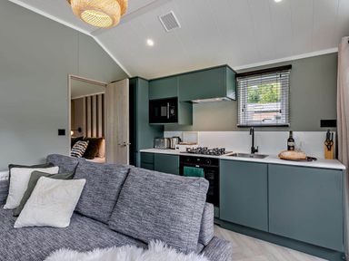 A kitchen with green cabinets and a sofa at Prion Spa, Llandyrnog