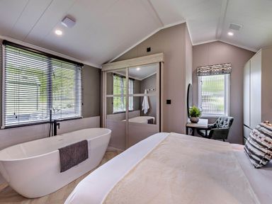 A bedroom with a bathtub and a chair at Prion Spa in Llandyrnog