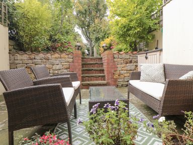 A patio area with chairs, a table, and steps at 21 High Street, Scarborough