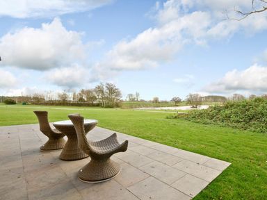 A patio area with a table and chairs overlooking a green field at Lawson in Aspatria