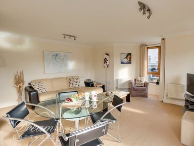 A living room with a sofa, dining table and television at Harbourside Apartment in Weymouth