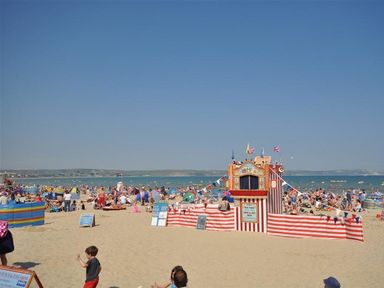 A crowded beach with umbrellas and a beach hut at Harbourside Apartment in Weymouth