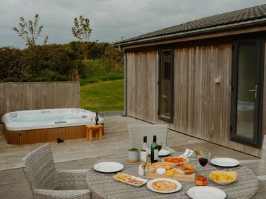 An outdoor patio with a hot tub and table set with food and drinks at Wellington in Wigton