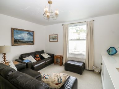 A living room with a sofa, table, and paintings at 58A South Ford Road in Dartmouth