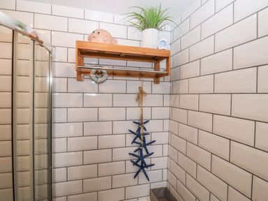 A bathroom with a shower and wooden shelf at 58A South Ford Road in Dartmouth