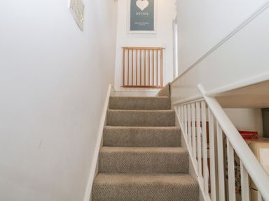A staircase with carpet and a wooden gate at 58A South Ford Road in Dartmouth