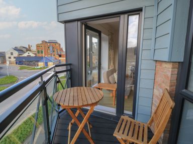 A balcony with a table and chair at Brewery View in Weymouth