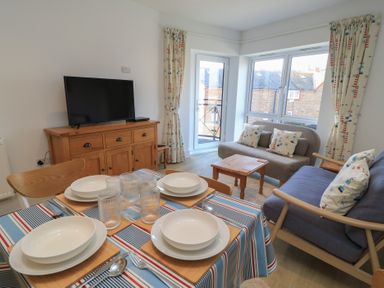 A living room with a television and dining table at Brewery View in Weymouth