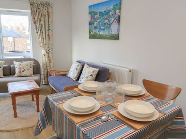 A dining room with a table set for meals at Brewery View in Weymouth