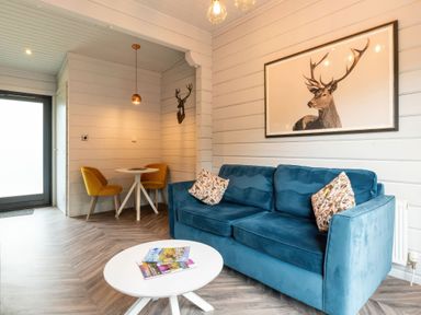A living room with a blue sofa and a dining area at Askrigg (Pet) Aysgarth