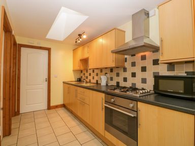 A kitchen with cabinets, oven, microwave, and sink at Dovecote Cottage, Corse near Gloucester