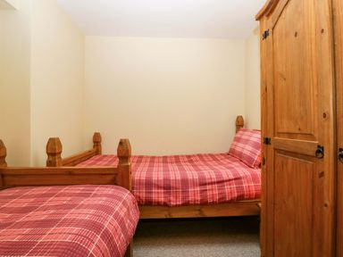 A bedroom with two beds and a wardrobe at Dovecote Cottage Corse near Gloucester