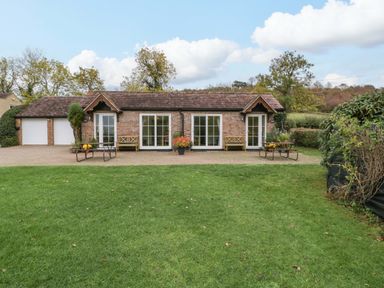 A cottage with a garden and benches at Dovecote Cottage in Corse near Gloucester