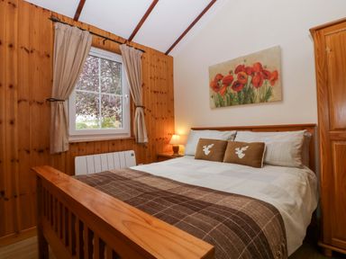 A bedroom with a bed and window at The Log Cabin in Corse near Gloucester