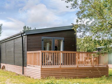 A cabin with a wooden deck and glass doors at Somersby Spa in Louth