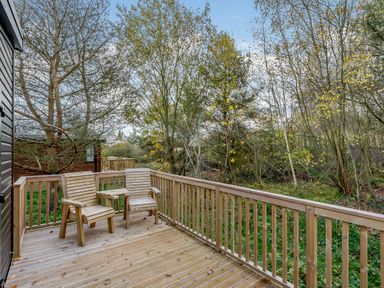 A deck with chairs surrounded by trees at Somersby Spa in Louth