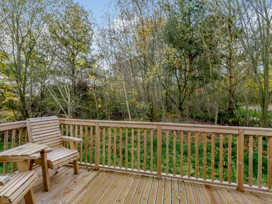 An outdoor deck area with wooden railing and chairs at Somersby Spa in Louth