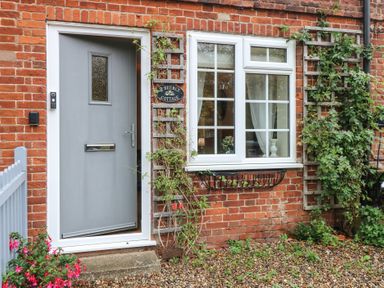 An outdoor entrance with a grey door and window at Beeble Cottage in Fakenham
