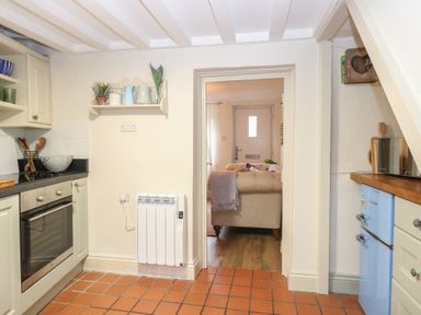 A kitchen with various appliances and view of living area at Beeble Cottage in Fakenham