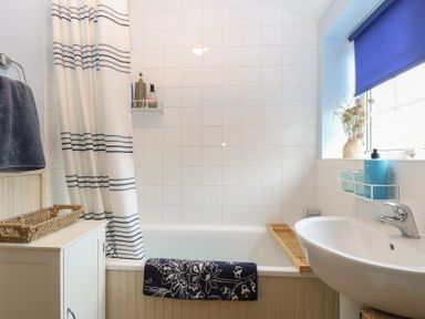 A bathroom featuring a bathtub, sink, and towels at Beeble Cottage in Fakenham