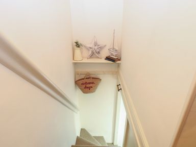 A staircase with a shelf holding a star and a boat at Beeble Cottage in Fakenham