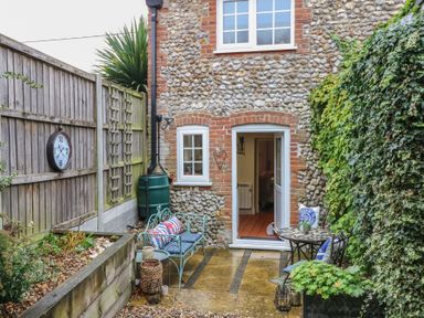 A garden area with a bench and table at Beeble Cottage in Fakenham