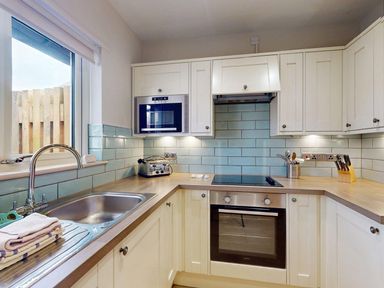 A kitchen with sink, oven, and microwave at Summerleaze Cottage 2 Spa Bude