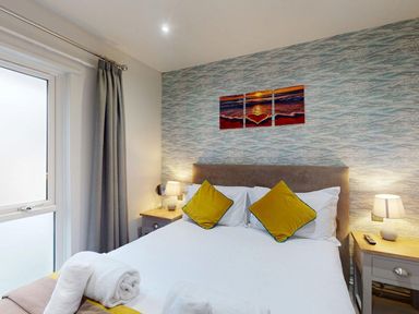 A bedroom with a bed and artwork on the wall at Summerleaze Cottage 2 Spa in Bude
