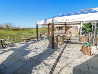 An outdoor patio with seating and tables at Glamping Pod 1 Oldwalls, Llanrhidian, Gower